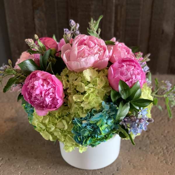 Pink peonies and hydrangeas arranged in a white vase