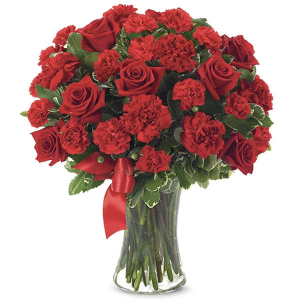 Red roses and carnations in a clear glass vase with a red ribbon