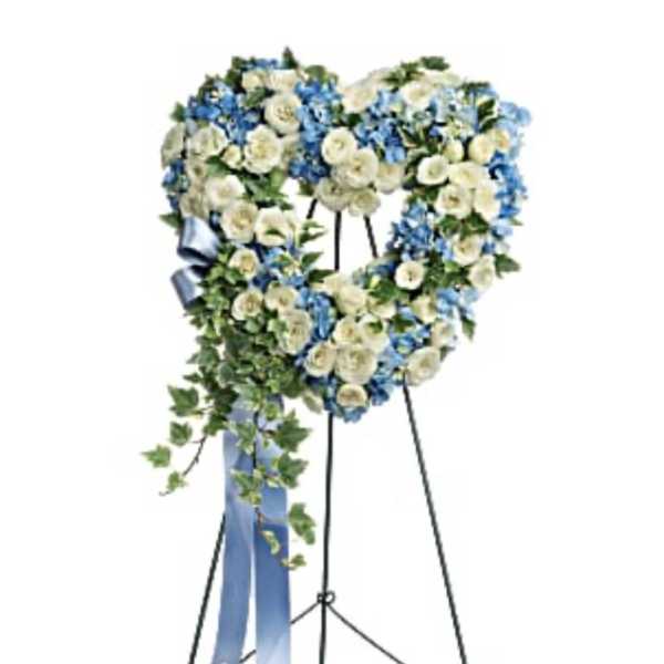 Heart-shaped floral wreath on a standing easel with blue and white flowers