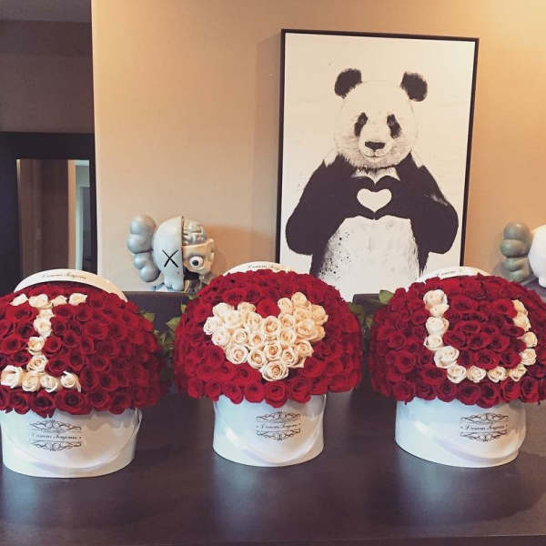 Three red and white rose hatbox arrangements spelling I heart U on a table