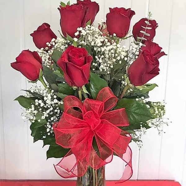 Red roses in a clear glass vase with a red bow