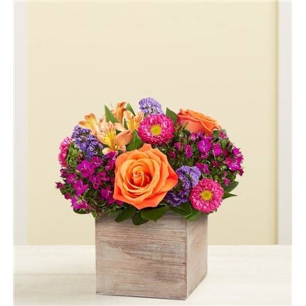 Orange roses and purple flowers arranged in a wooden box
