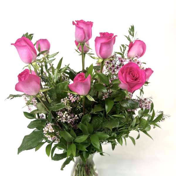 Pink roses in a clear glass vase with small filler flowers