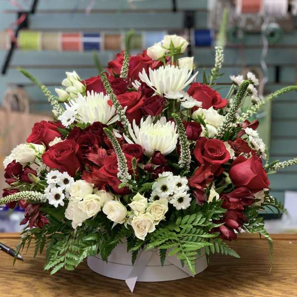 Red and white mixed flower arrangement in a round box