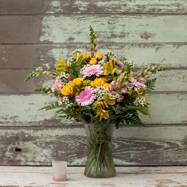Mixed bouquet of pink and yellow flowers in a glass vase