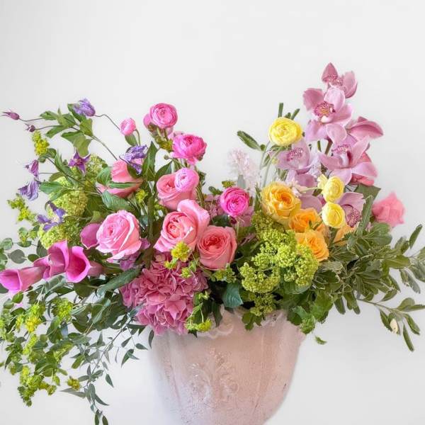 Large mixed bouquet in a pink vase with pink, yellow, and purple flowers