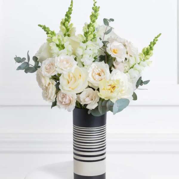 White floral arrangement in a striped black-and-white vase