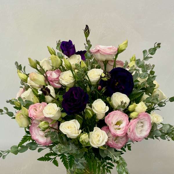 Bouquet of pink, white, and deep purple flowers in a glass vase