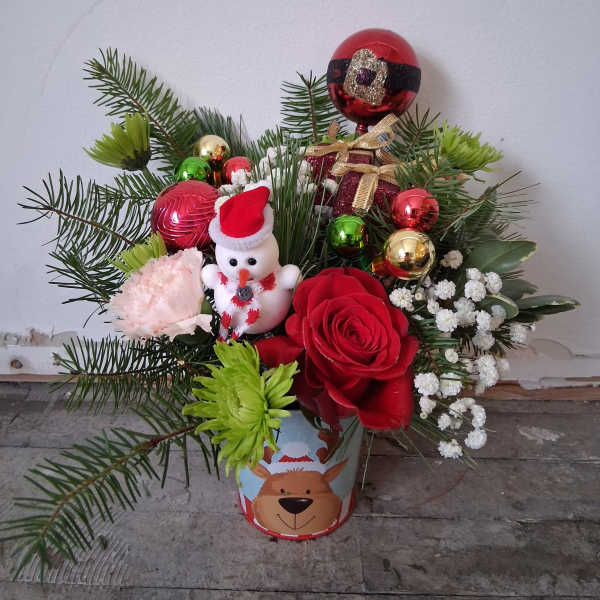 Christmas arrangement with red roses, a snowman ornament, and festive baubles in a decorated tin