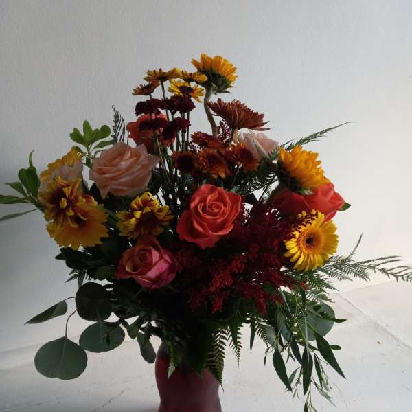 Mixed bouquet of roses and daisies in a red vase