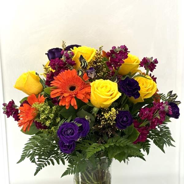 Bouquet of yellow, purple, and orange flowers in a clear glass vase
