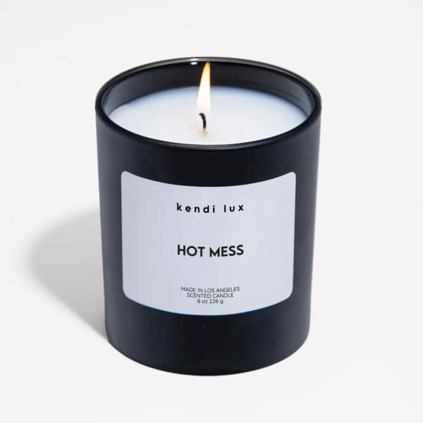 Lit black scented candle in a glass jar with a white label