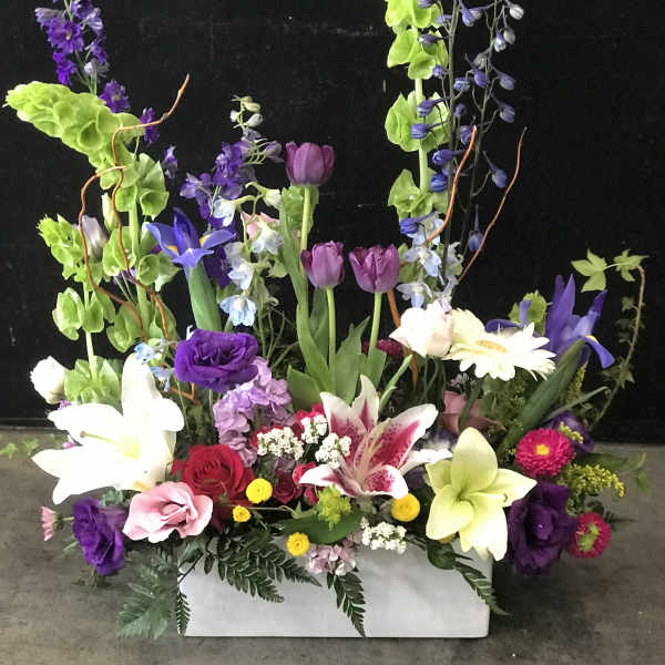 Tall mixed floral arrangement in a white rectangular container