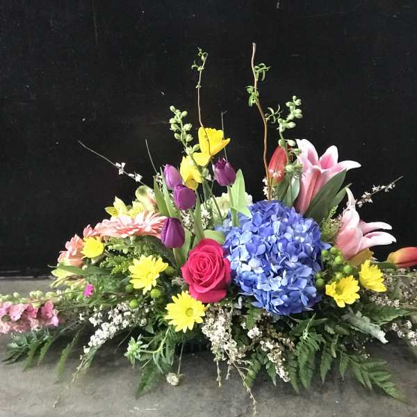 Colorful floral centerpiece with hydrangea, roses, lilies, and daisies