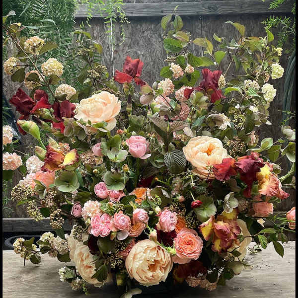 Large bouquet of peach, pink, and burgundy flowers with mixed greenery