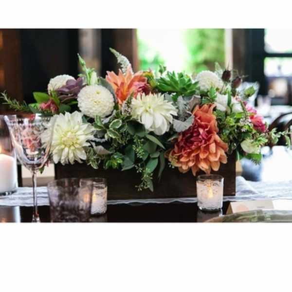 Low floral centerpiece with white and peach blooms in a dark rectangular container