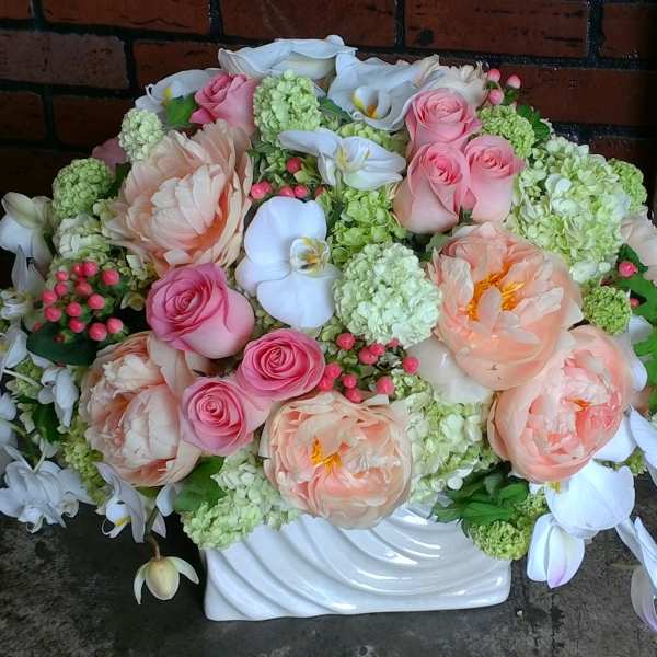 Large pastel floral arrangement in a white vase with pink and white blooms