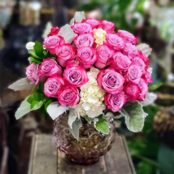 Pink rose bouquet in a glass vase with white hydrangea accents