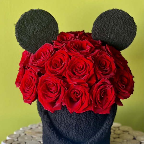 Red roses arranged in a black bear-shaped container with round ears