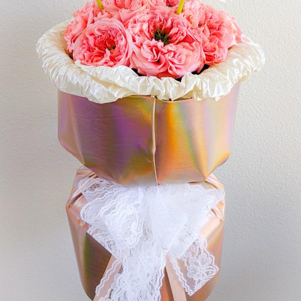 Pink roses in a metallic gift box with white flowers on top