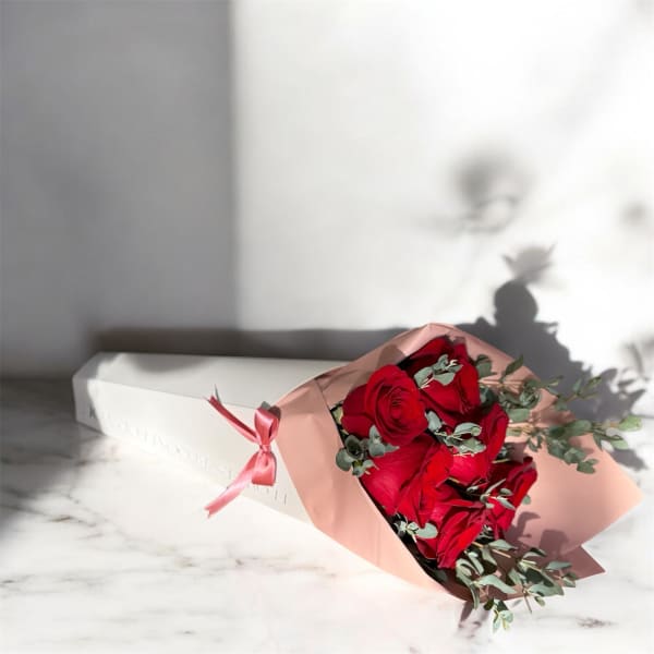 Bouquet of red roses wrapped in pink paper