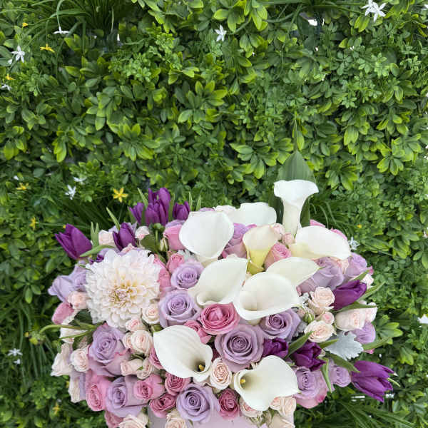Lavender and pink roses with white calla lilies in a pale pink box