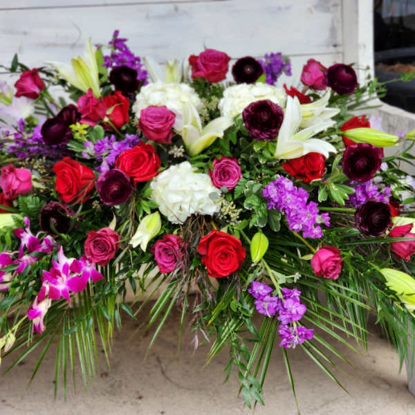 Large mixed floral arrangement with roses, lilies, and purple blooms