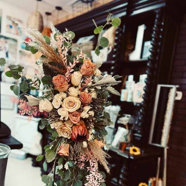 Tall bouquet of peach and cream roses with eucalyptus and dried grasses