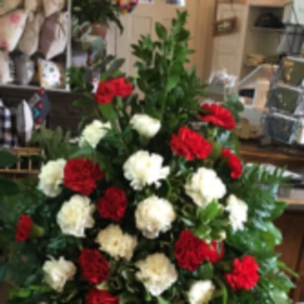 Standing floral spray of red and white carnations on a metal easel