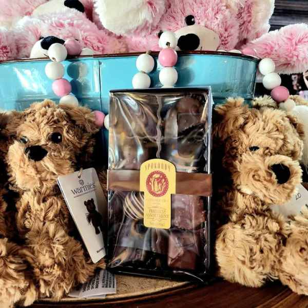 Plush teddy bears arranged around a box of chocolates in a basket
