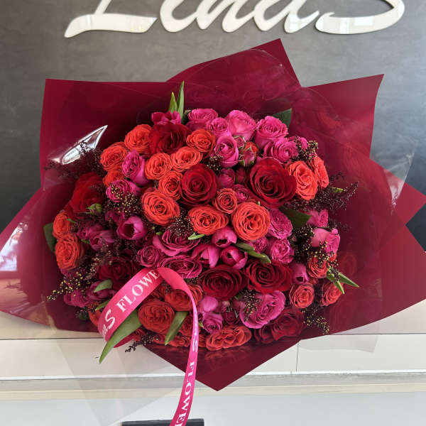 Large bouquet of red and pink roses wrapped in burgundy paper