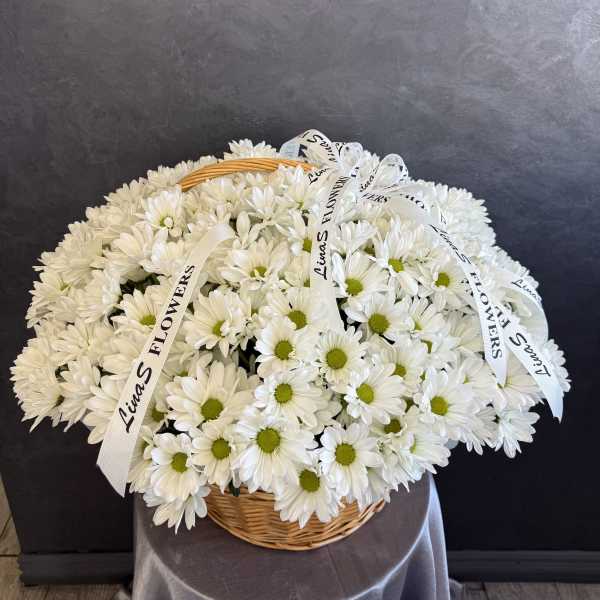 White daisy bouquet in a wicker basket with ribbon bows