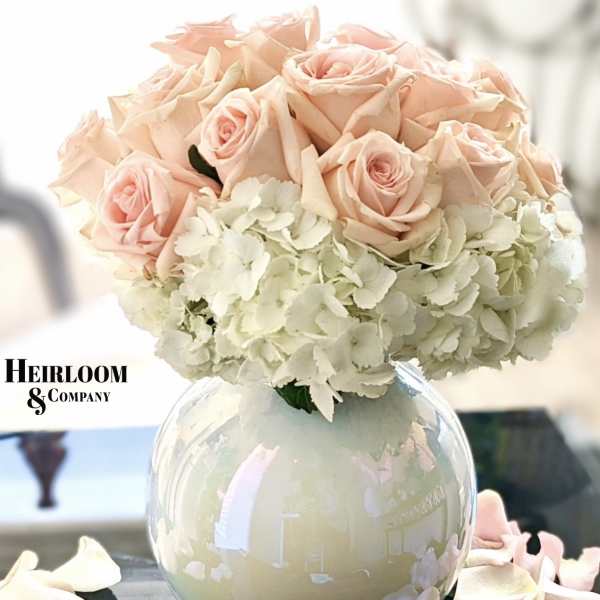 Blush pink roses and white hydrangeas in a round glass vase