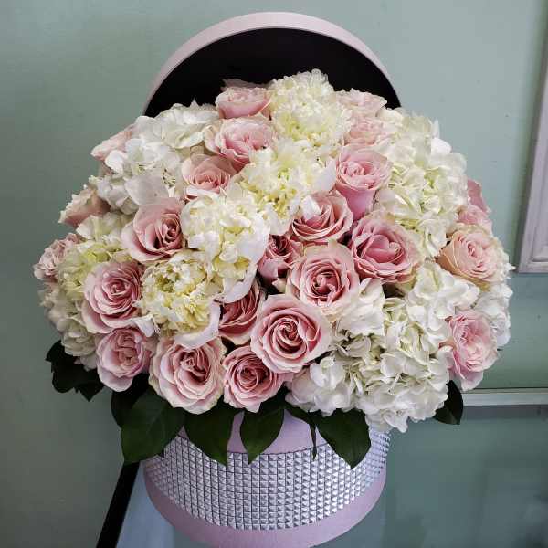 Pink roses and white hydrangeas in a round pink hatbox