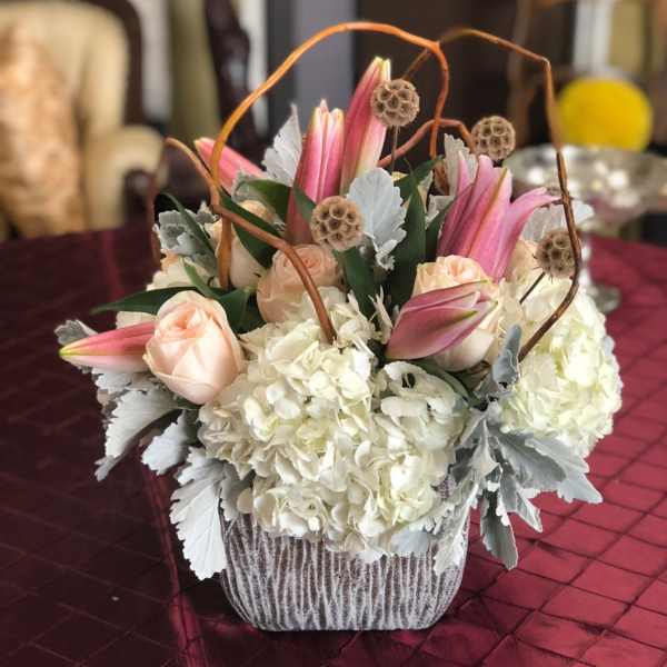 Pink lilies and pale roses arranged with white hydrangeas in a basket