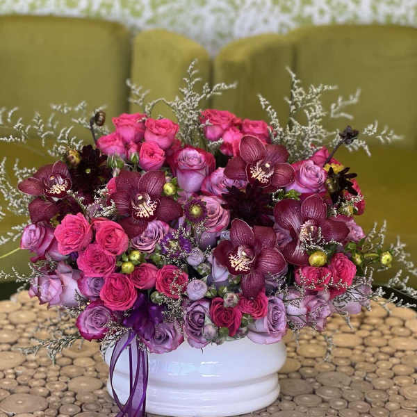 Pink and purple rose bouquet with dark orchids in a white vase