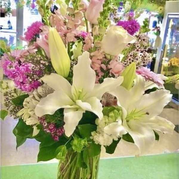 Tall bouquet of white lilies and pink flowers in a glass vase