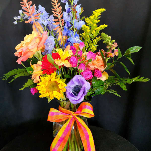 Colorful mixed bouquet in a glass vase with a striped ribbon