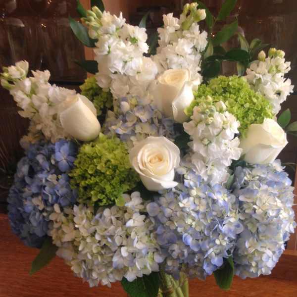 Vase arrangement of white roses, white stock, and green and blue hydrangeas