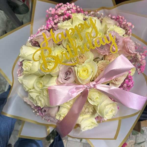 Bouquet of pale roses with a pink ribbon and "Happy Birthday" topper
