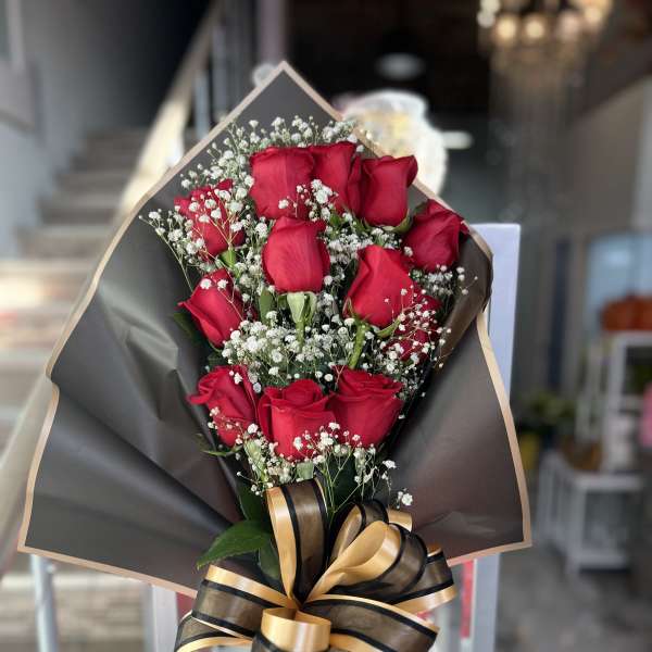 Bouquet of red roses with baby's breath and a black-and-gold ribbon