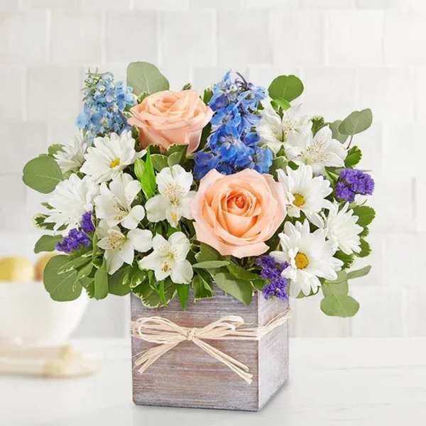 Peach roses and white daisies in a wooden box