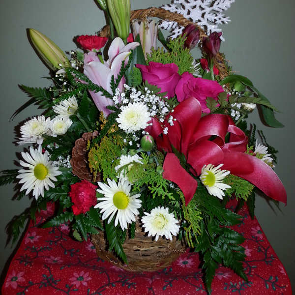 Basket arrangement with lilies, roses, daisies, and a red ribbon
