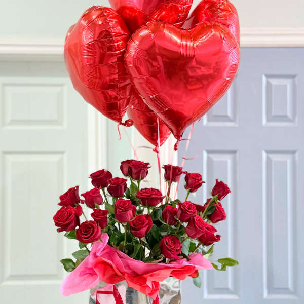 Red roses in a silver gift bag with red heart balloons