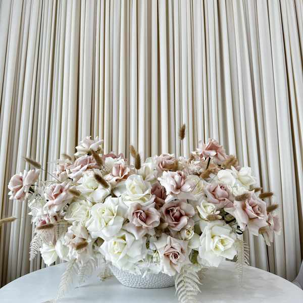 Large arrangement of pale pink and white roses in a white bowl vase