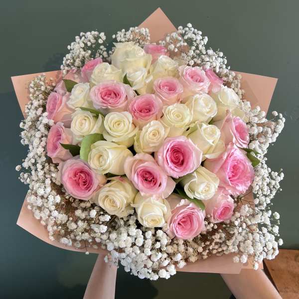 Bouquet of pink and white roses with baby's breath in pink wrap
