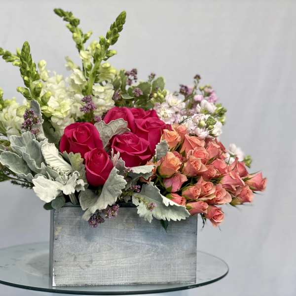 Mixed bouquet of pink and peach roses in a rectangular metal container
