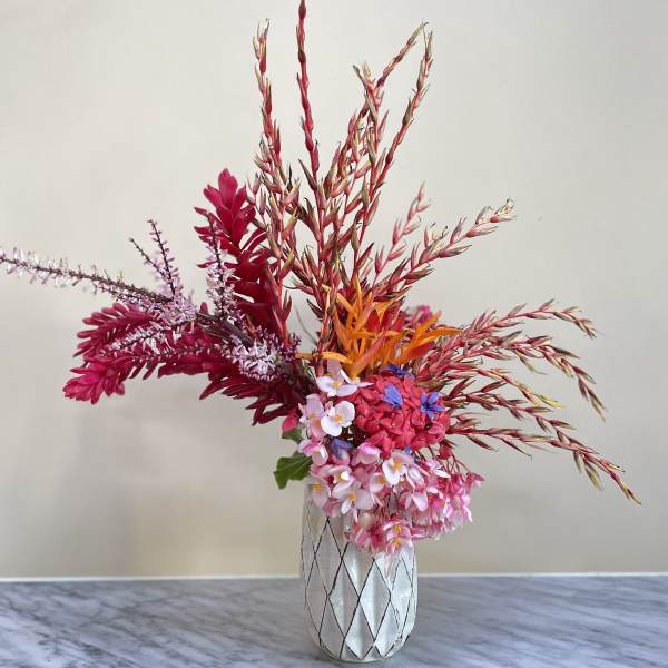 Colorful floral arrangement in a patterned vase with tall red stems