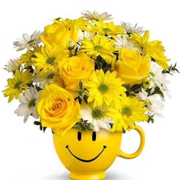 Yellow roses and daisies in a smiley-face mug