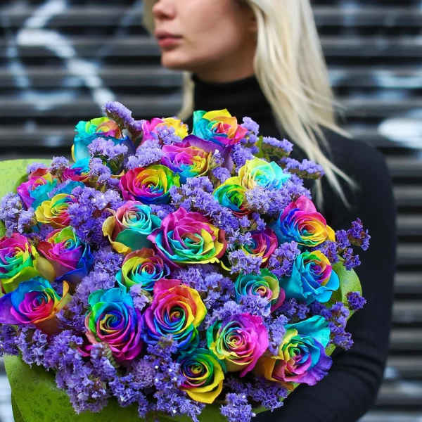 Bouquet of rainbow-colored roses with purple filler flowers